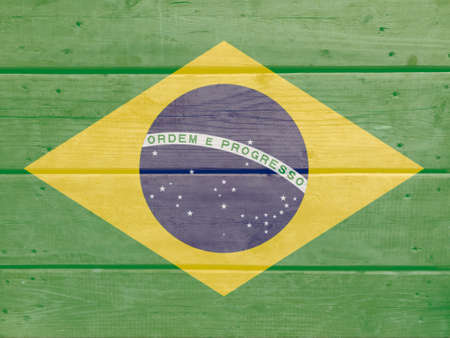 Brazil flag painted on wood plank background. Brushed natural light knotted wooden board texture. Wooden texture background flag of Brazilの写真素材