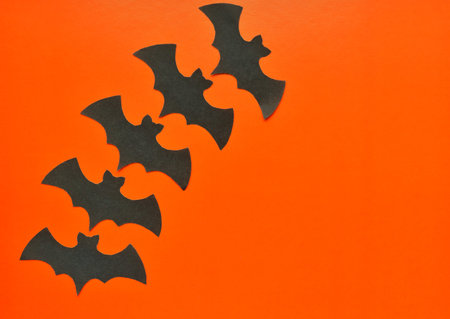 Black paper bats lie on an orange background