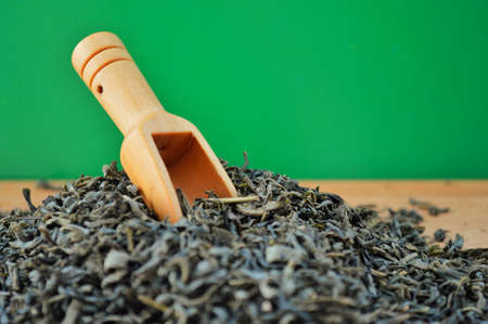 Wooden spoon in a heap of loose tea on wooden background. Against the background of a green chromakeyの写真素材