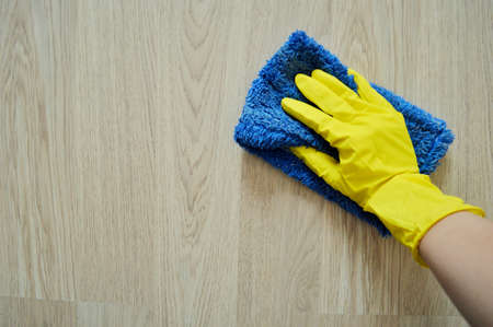 Hand in a rubber yellow glove washes the floor with a rag.の写真素材