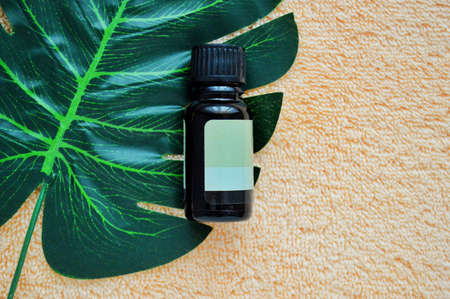 Dark glass bottle lying on palm leaf on a background of beige fabric.の写真素材