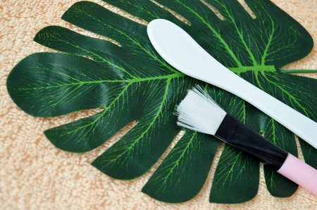 Shovel and brush for applying the mask lie on palm leaf on a background of beige fabric