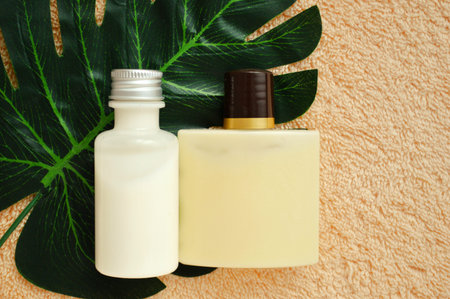 Plastic bottles lie on a palm leaf on a beige fabric background