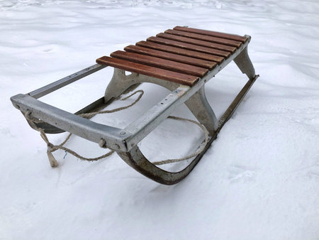 Old children's sleds are standing in the snow on a winter day.