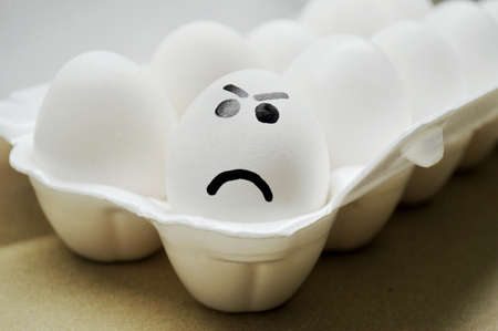 White egg with painted angry face in the tray.の写真素材