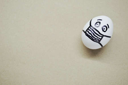 White egg with painted face wearing a mask on wooden background.の写真素材