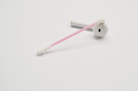 Wireless earphone and cotton swab on a white background. Cleanliness concept.