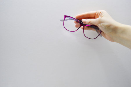 Female hand holds glasses on white background with copy space.