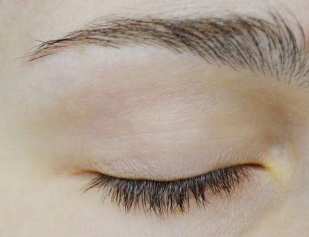 Beautiful closed female eye and brown eyebrow close up.の写真素材