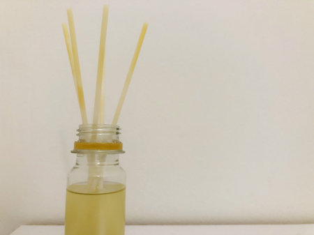 Wooden aroma sticks in a glass flask filled with flavor liquid substance isolated over white...