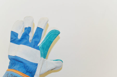 blue work cloth glove against a white wall background.