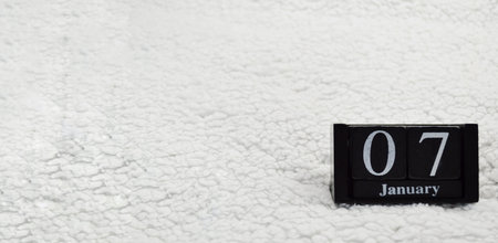 Wooden calendar from blocks on a white textile background with copy space. Banner. 7th of January....