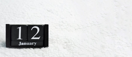 Wooden calendar from blocks on a white textile background with copy space. Banner. 12th of January....