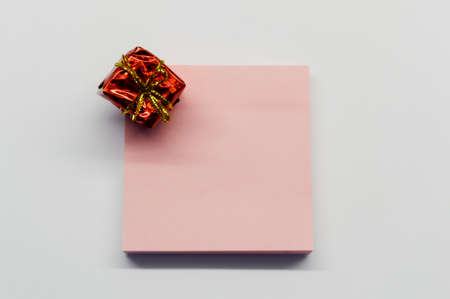 Red shiny little gift and paper for notes on white background.の写真素材
