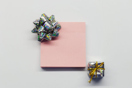 Silver shiny bow for gift and silver shiny little gift on paper for notes on white backgroundの写真素材