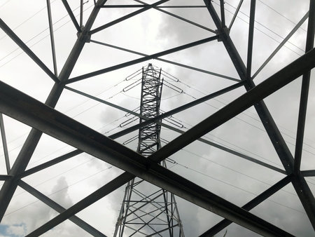 Inspection of a metal high-voltage pole from bottom to top against a blue sky. Power networks for...