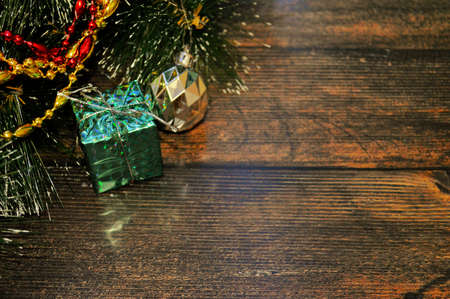Christmas background of dark wood with fir branches,gift,ball,red and gold beadsの写真素材