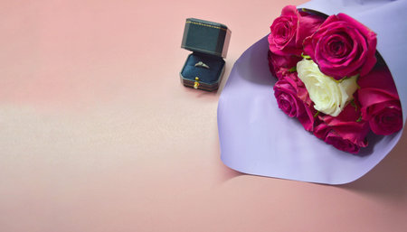 Bouquet of red roses in purple package and box with a ring lie on pink background. Concept of...