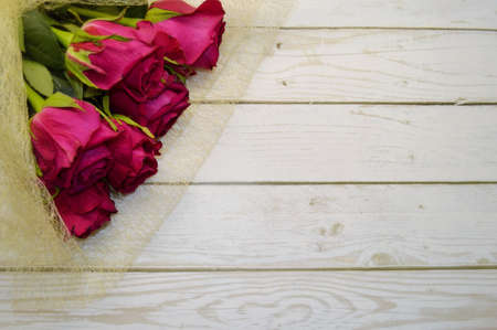 Bouquet of red roses lies on white wooden background.の写真素材