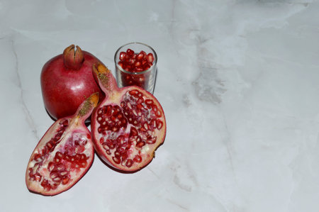 Fresh juicy red pomegranate on white marble background.