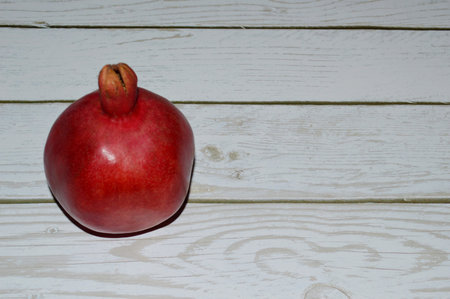 Fresh juicy red pomegranate on white wooden background.