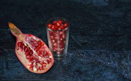 Fresh juicy red pomegranate on dark black concrete background.の写真素材