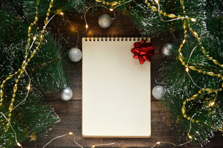 Blank white notebook with red bow on dark wooden background with fir branches and silver Christmas balls. Catholic Christmas Ever. Christmas Card Day. new year. Christmas Lights Dayの写真素材