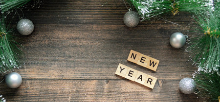word new year from wooden letters on a dark wooden background with fir branches and silver Christmas balls. Catholic Christmas Ever. Christmas Card Day. Bannerの写真素材