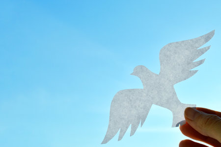 White paper origami bird on blue sky background. World Day of Peace. Day Against Humiliation. International Day Of Human Fraternity. International Day of Living Together in Peaceの写真素材