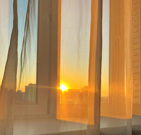 Sunset through the transparent curtains on the window. World Sun Day