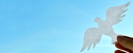 White paper origami bird on blue sky background. World Day of Peace. Day Against Humiliation. International Day Of Human Fraternity. International Day of Living Together in Peace. Bannerの写真素材