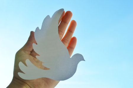 White paper origami bird on blue sky background. World Day of Peace. Day Against Humiliation. International Day Of Human Fraternity. International Day of Living Together in Peaceの写真素材