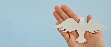 White paper origami bird on blue background. World Day of Peace. Day Against Humiliation. International Day Of Human Fraternity. International Day of Living Together in Peace. Bannerの写真素材