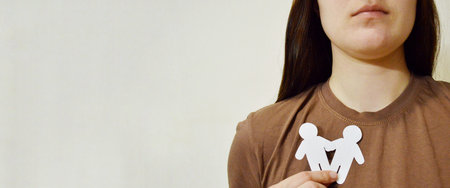 Girl holding paper man on her chest. Day Against Humiliation. International Day Of Human Fraternity....