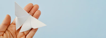 White paper origami butterfly on blue background. World Day of Peace. Day Against Humiliation. International Day Of Human Fraternity. International Day of Living Together in Peace. Bannerの写真素材