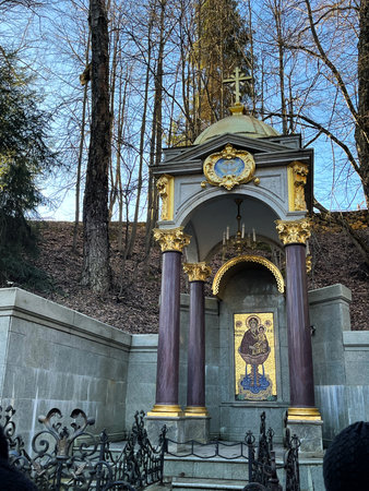 Ornate structure with golden dome and cross, surrounded by trees, showing intricate architectural details and religious symbolism in a serene outdoor settingの写真素材