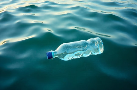 Transparent plastic water bottle floating in clear blue ocean water, surrounded by bubbles, illustrating pollution impact on marine environments and the need for sustainability.の素材