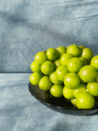 Vibrant green grapes displayed in a sleek black bowl, emphasizing their freshness and glossy texture, creating an inviting and appetizing visual experienceの写真素材