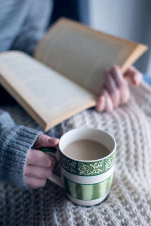 Person is reading a book and drinking coffeeの写真素材
