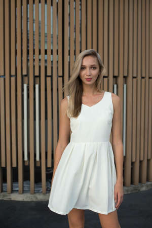 Pretty blond girl standing next to the brown wallの写真素材
