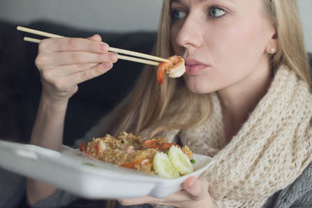 Young woman eating seafood at homeの写真素材
