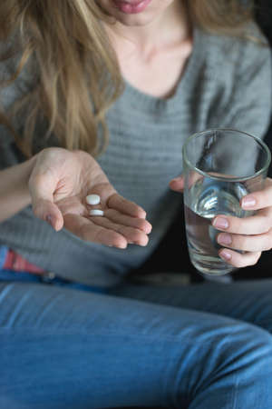 Young girl holding pill and glass of waterの写真素材