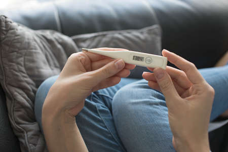 Woman holding thermometer with high feverの写真素材