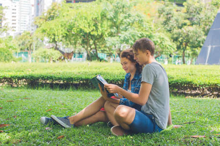 Young couple reading a book outdoorの写真素材