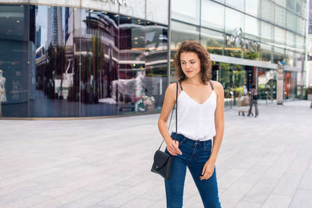 Young lady standing next to the modern bulding and looking to the sideの写真素材