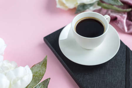 Cup of coffee on the black notebook with flowers. Planing to do list. Flat lay. Woman workplace.の写真素材