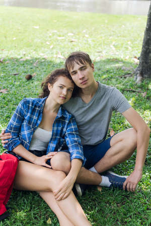 Couple of college students sitting on the grassの写真素材