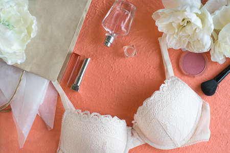 Light pink bra and make up products on the peach color background.の写真素材