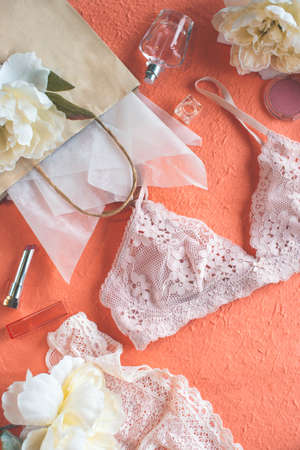 Pink bra, paper bag, flowers on the peach color background. Giftの写真素材