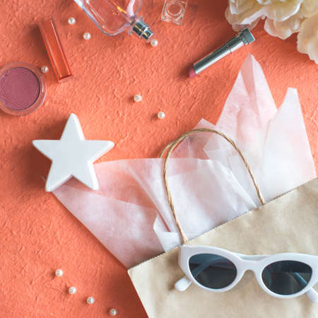 Paper bag, make up and perfume on the peach color backgroundの写真素材